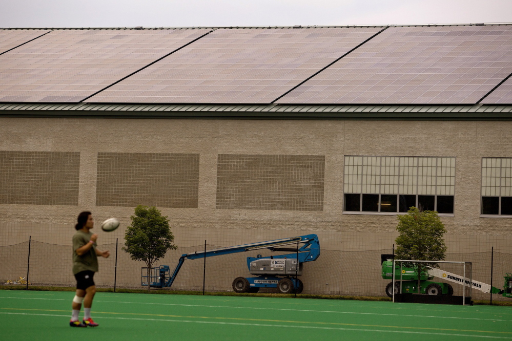 Josh Kim, a junior at Bowdoin College, tosses a rugby ball in front of newly installed solar panels atop Watson Arena in Brunswick last month.
2014 Press Herald File Photo/Gabe Souza