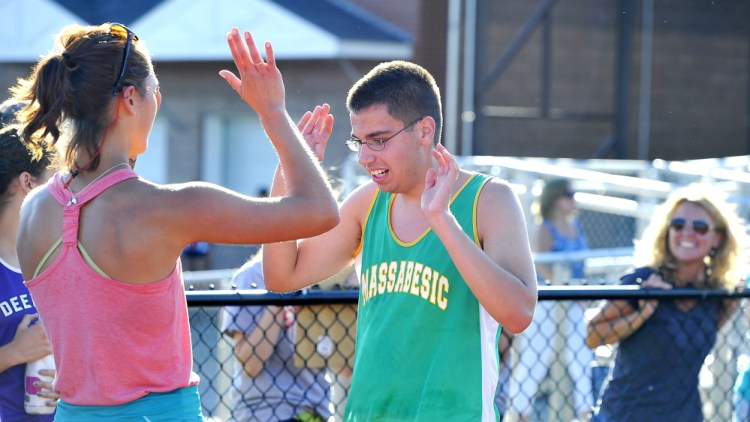 Massabesic junior Noah Harfoush, left, is greeted by assistant coach Sam Person after finishing the SMAA Relays at Thornton Academy last week. Harfoush, who is autistic, is one of three special needs runners on the Mustangs this season.