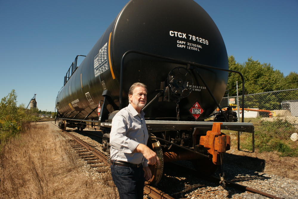 John Giles, president and CEO of the Central Maine & Quebec Railway, walks behind a tank car carrying propane as he inspects work in Hermon. Giles wants to modernize the railroad so it can operate efficiently, carrying lumber and other forest products as its primary cargo.