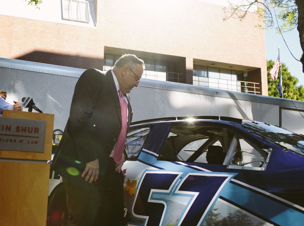 Gov. Paul LePage examines the model of NASCAR driver Austin Theriault's stock car in Portland on Friday. The "Maine Car," which is the first public-private sponsored car, was unveiled during a news conference where LePage spoke. Whitney Hayward/Staff Photographer