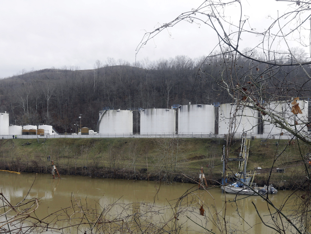 Workers inspect an area outside a retaining wall around storage tanks where a chemical leaked into the Elk River in Charleston, W.Va., last January.