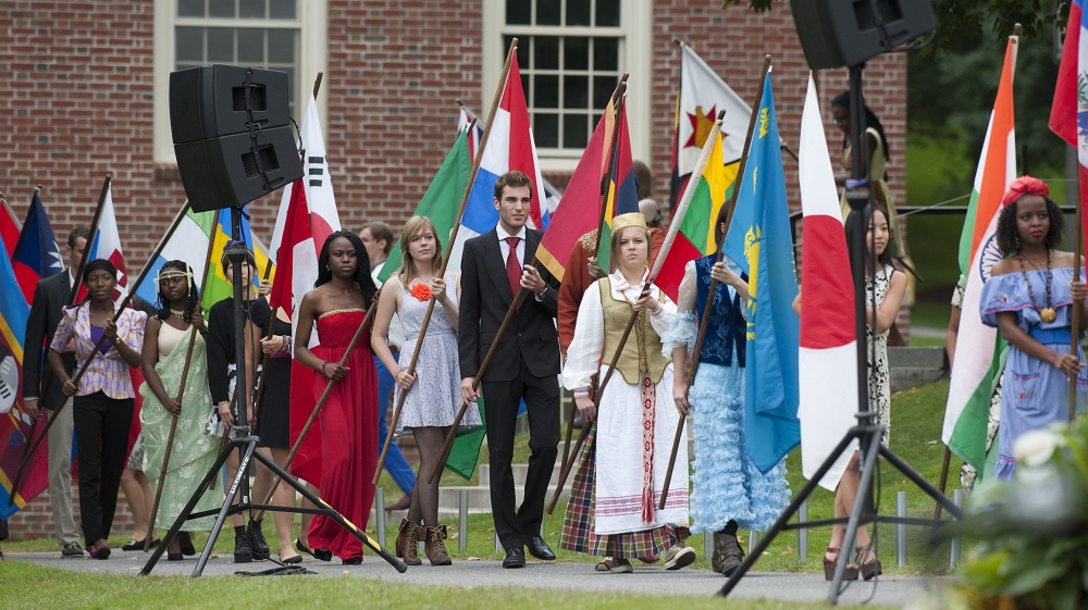 Colby College students from around the globe carry flags of their countries Saturday as they lead the processional for incoming President David Greene at the college in Waterville.