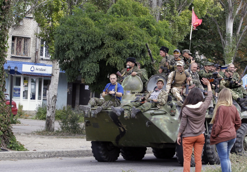 Residents wave to Pro-Russian rebels atop an armored personal carrier during a Sundy parade in Luhansk, where some semblance of normality has returned.
