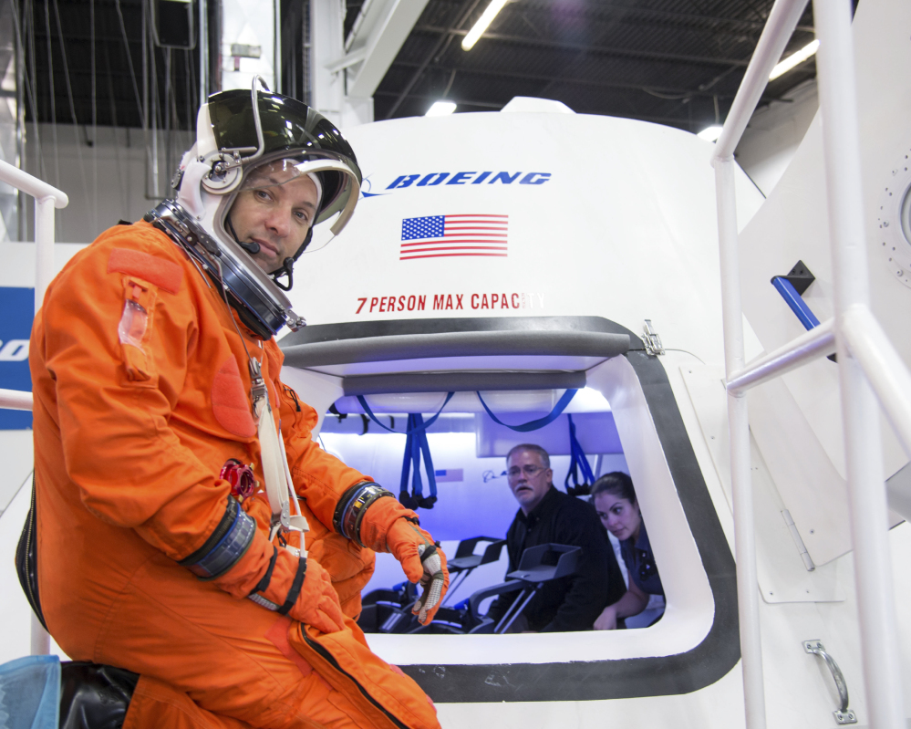 Astronaut Randy Bresnik prepares to enter Boeing’s CST-100 capsule for a fit check evaluation at the company’s Houston Product Support Center. NASA will pay Boeing $4.2 billion and SpaceX $2.6 billion to certify, test and fly their crew capsules.