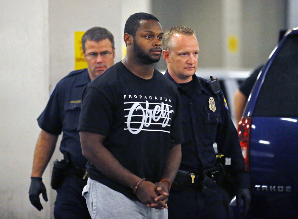 Phoenix police officers escort Arizona Cardinals running back Jonathan Dwyer to the 4th Avenue Jail after his arrest Wednesday. Dwyer is charged with aggravated assault in connection with two altercations at his home in July involving a woman and their 18-month-old child.