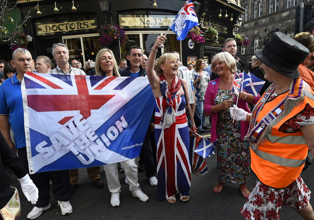A woman waves a flag as members of the Orange Order march past during a pro-Union rally in Edinburgh on Saturday. The vote on Scottish independence takes place Thursday, and about 90 percent of eligible voters are expected to cast ballots.