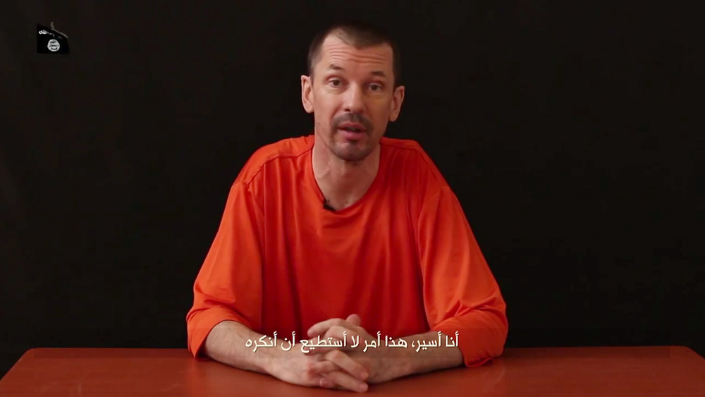 In this still image taken from an undated video published on the Internet by Al-Furqan, the media arm of the Islamic State group militants, captive British journalist John Cantlie speaks into the camera on the first of what he says will be a series of lecture-like “programs” in which he says he will reveal “the truth” about the Islamic State group. The Arabic subtitle reads “I am a prisoner and that is something I will not deny.”