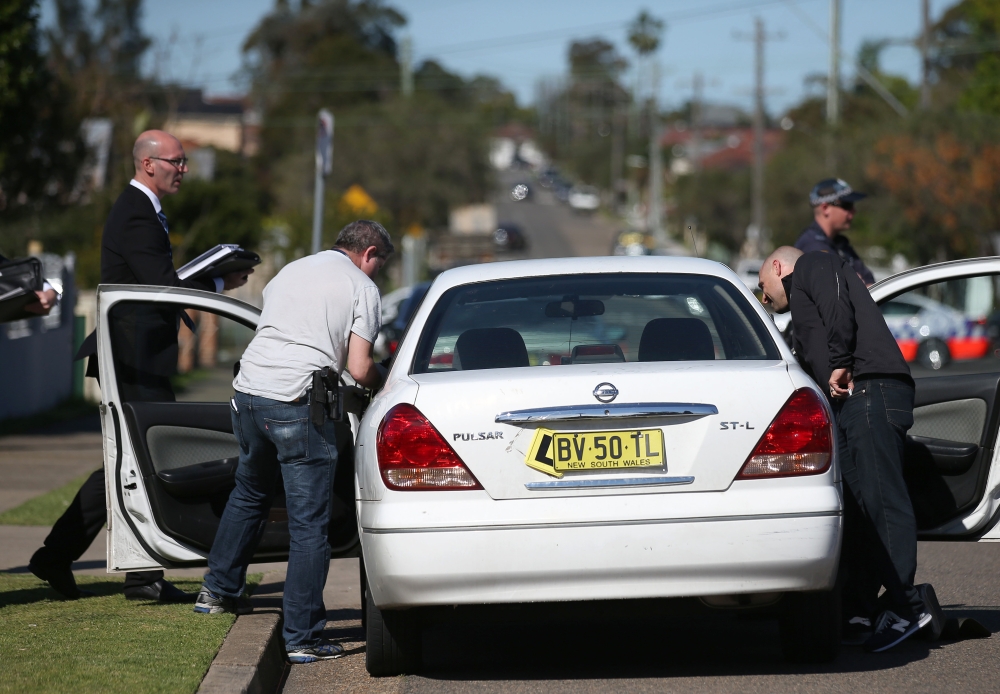 Police investigators search a car at a home at Guildford in suburban Sydney, Australia, after 800 federal and state police officers raided more than two dozen sites Thursday.