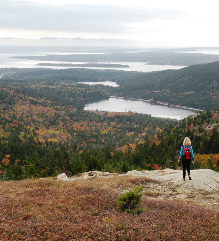 A hiker atop Gilmore Peak at Acadia National Park enjoys the amazing views that come with finding your way to the various peaks in this to-die-for section of Maine.