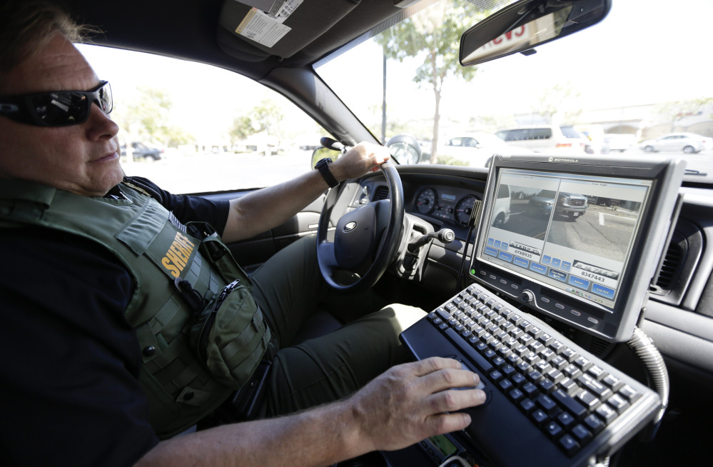 San Diego County Deputy Sheriff Ben Chassen looks at a monitor as his vehicle reads license plates of cars in a parking lot in San Marcos, Calif. A San Diego man is suing the San Diego Association of Governments for records collected on his vehicle.