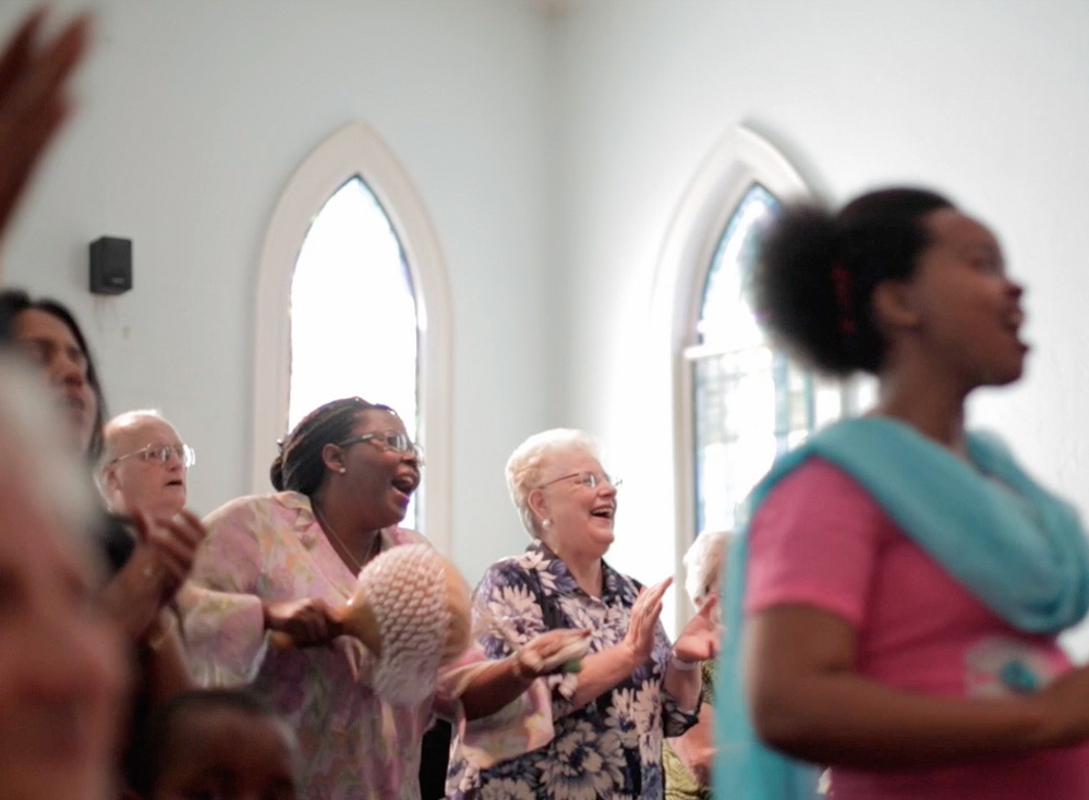 Angie Guillette, center, and fellow church members worship at the First Assembly of God church on Cumberland Avenue in Portland. Each week after the Sunday service, Guillette and others help distribute food to hundreds of families in the inner city neighborhood.