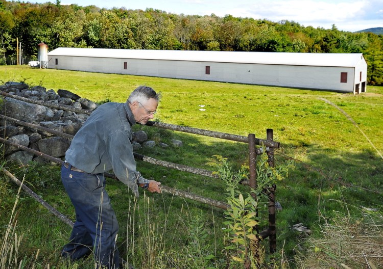 Russ Florenz closes the gate to a grazing pasture in Paris, where his unused 300-foot-long chicken barn will get 200 solar panels installed as part of the first community solar farm in Maine.
