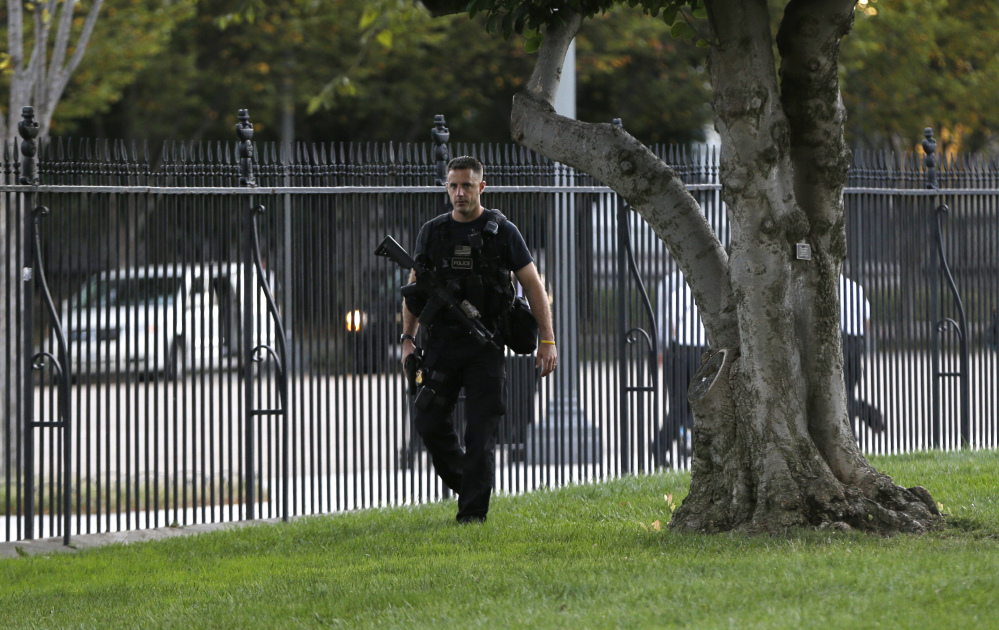 An armed member of a security detail walks along the interior of the perimeter fence on White House North Lawn along Pennsylvania Avenue in Washington on Monday, part of tightened security.