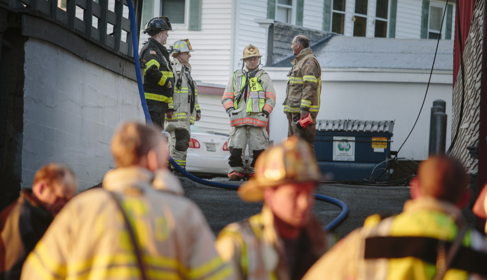 Firefighters talk Thursday after putting out a fire at 35 Main St. in Biddeford. A 23-year-old man was killed and another person was critically injured in the arson fire, the first of two in the city that came four days apart.