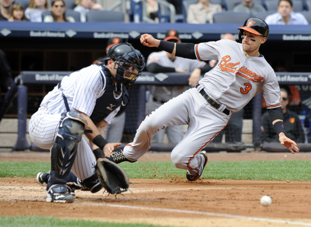 The Baltimore Orioles’ Ryan Flaherty scores on a single by Nick Markakis as Yankees catcher Francisco Cervelli takes the throw in the fourth inning of Wednesday’s game in New York. Baltimore scored six runs in the inning.