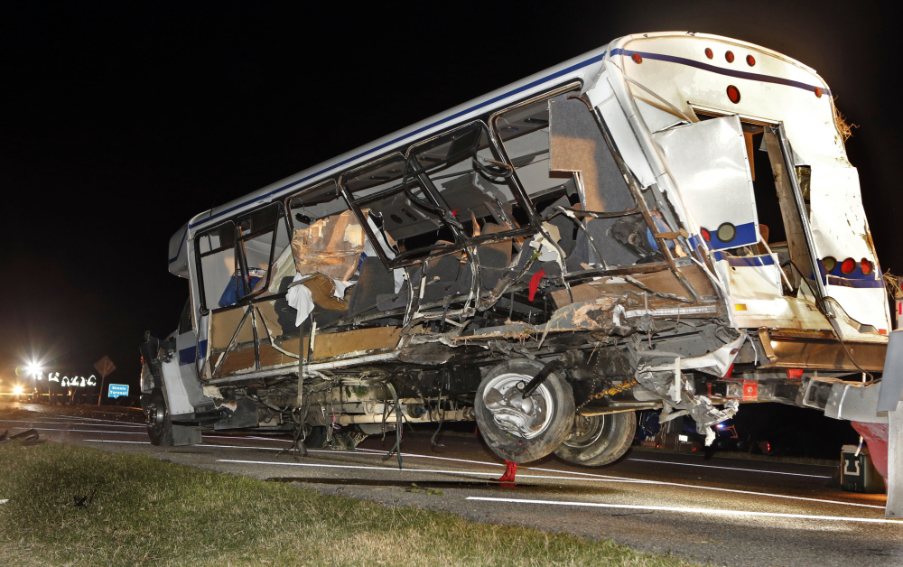 A wrecker removes the team bus as Oklahoma Highway Patrol and emergency personnel work the scene of an accident just south of the Turner Falls area on Saturday.  Four members of a Texas college softball team died after a tractor trailer crossed over the center median on Interstate 35 and collided with the team’s bus Friday night.