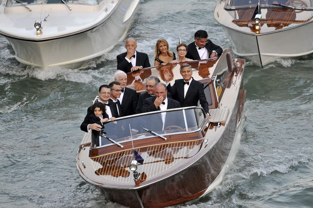 Actor George Clooney, right, waves from a boat with Ramzi Alamuddin, third from right front row, father of his fiancee Amal Alamuddin, his father Nick Clooney, fourth from right front row, and his mother Nina Bruce, second from right back row, on their way to the Aman hotel ahead of his wedding in Venice, Italy, on Saturday.
