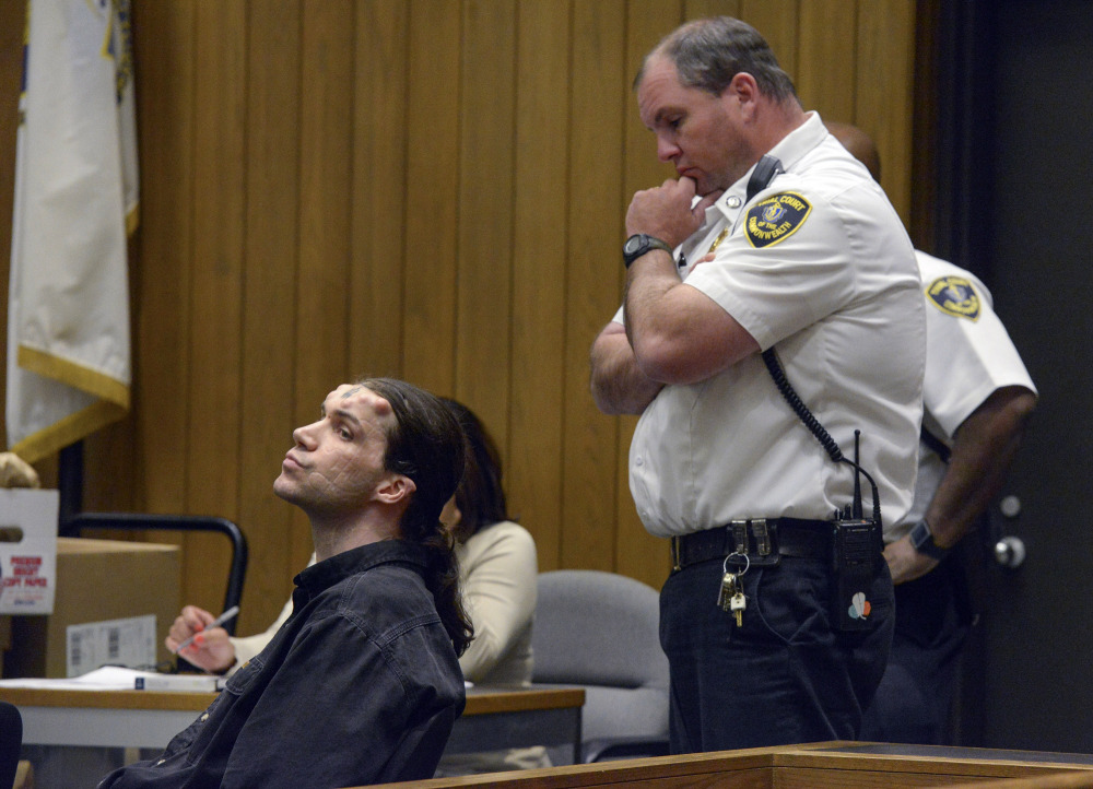Caius Veiovis, seated, reacts to guilty verdicts in his triple-murder trial Friday in Hampden Superior Court in Springfield, Mass. He is the third of three defendants in the 2011 killings.