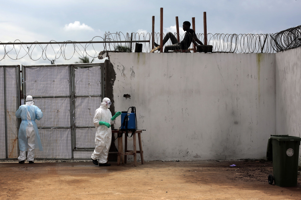 Health workers stand outside the Island Clinic Ebola isolation and treatment center in Monrovia, Liberia, on Friday. The outbreak has overwhelmed the health care system.