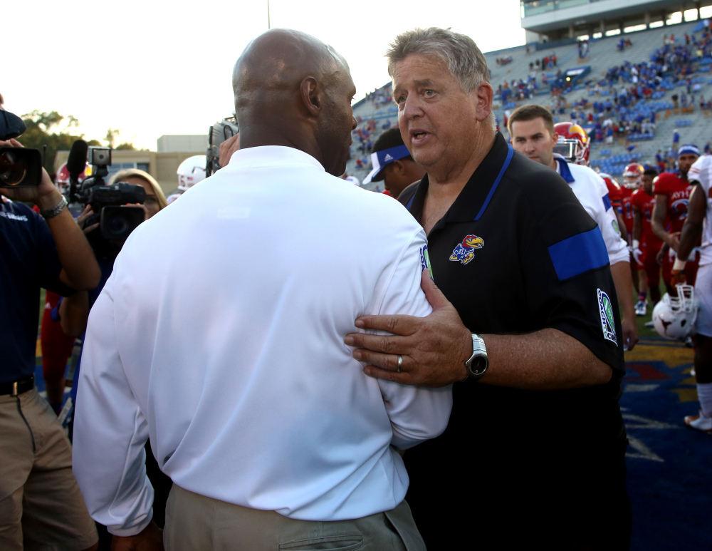 Texas Coach Charlie Strong, front, and Kansas Coach Charlie Weis meet on the field after an NCAA football game on Saturday in Lawrence, Kan. Texas won 23-0. Weis was fired on Sunday.