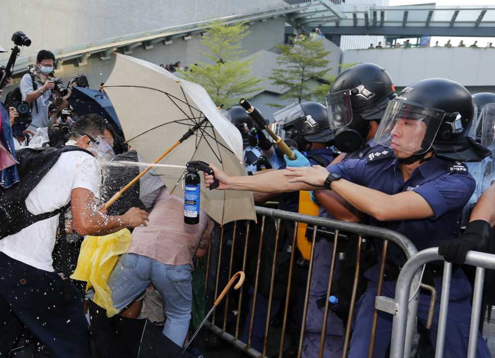 An anti-riot policeman, right, shoots pepper spray at a pro-democracy demonstrator outside the government headquarters in Hong Kong on Sunday.