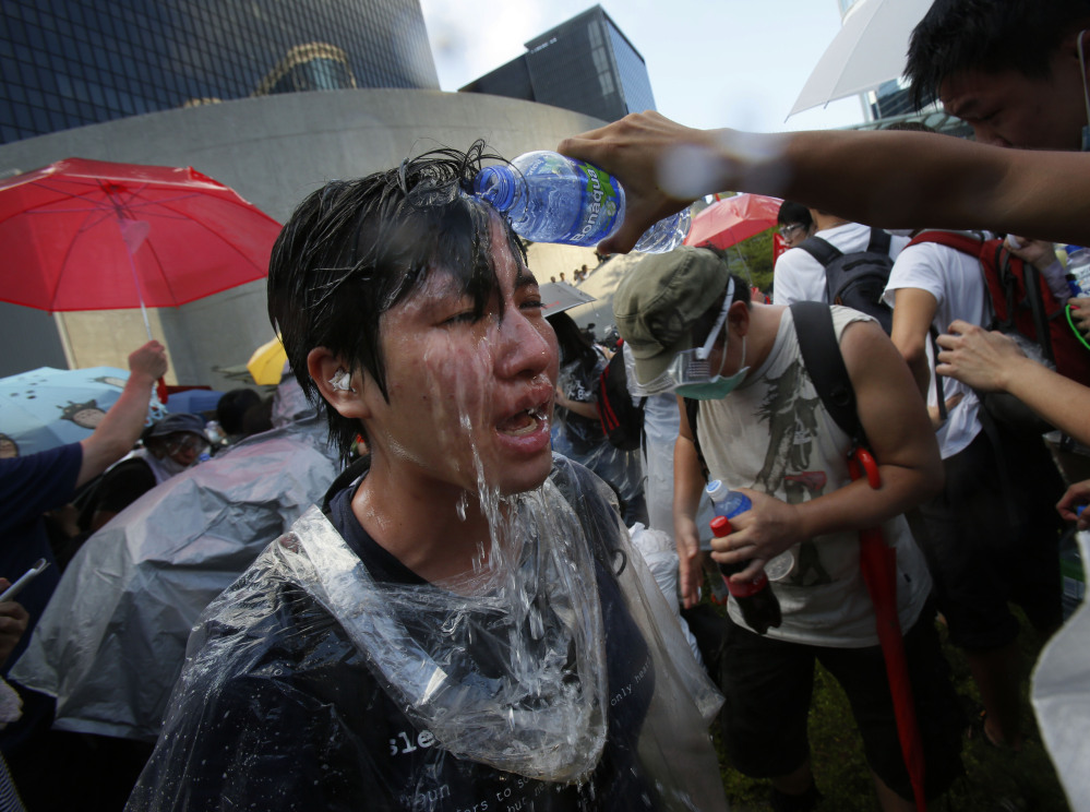 A student protester is overcome by pepper spray from anti-riot police as thousands of protesters surround the government headquarters in Hong Kong on Sunday.