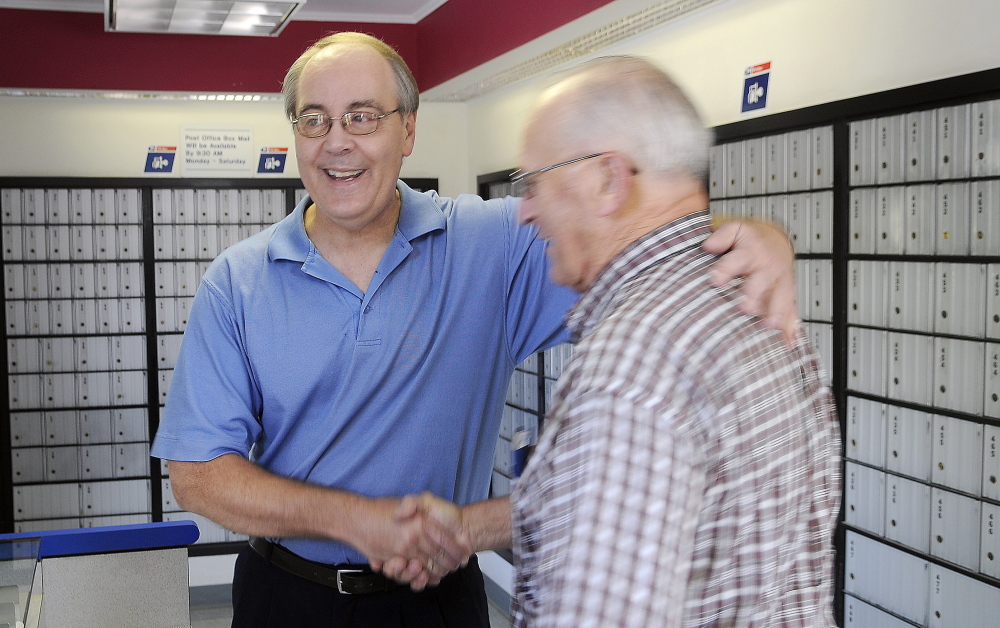 Customer Dick Poulin, right, congratulates retiring Postmaster David Shepherd at the post office Monday. “He takes care of the customers like you would not believe,” Poulin said.