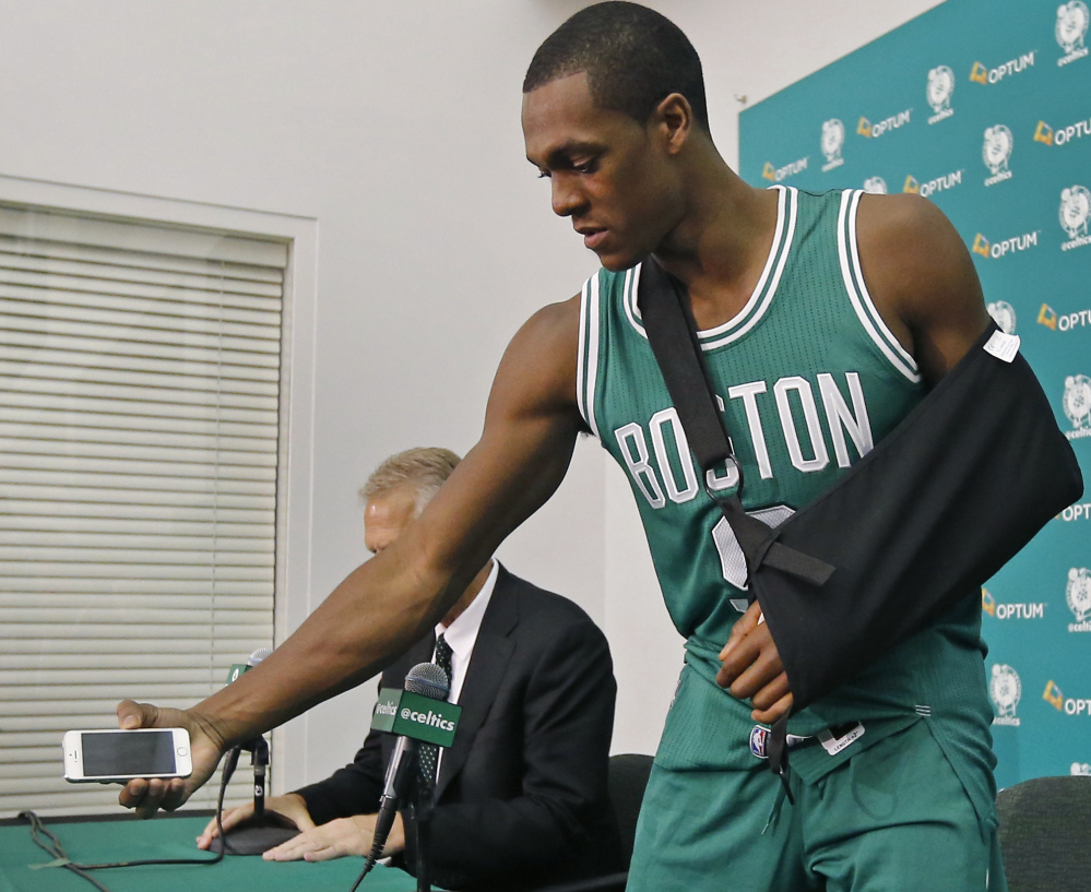 Boston’s Rajon Rondo, recovering from hand surgery, picks up his cellphone after taking questions from reporters during the Celtics media day Monday in Waltham, Mass.