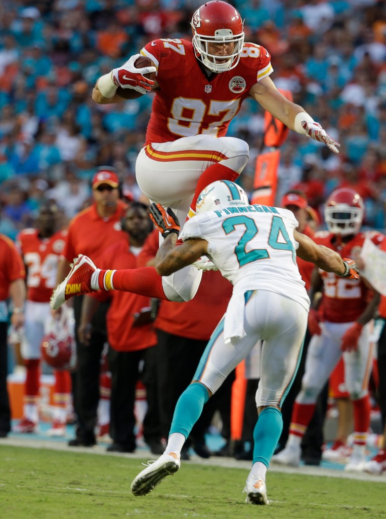 Kansas City Chiefs tight end Travis Kelce (87) jumps to avoid a tackle by Miami Dolphins cornerback Cortland Finnegan (24) during a game Sunday in Miami Gardens, Fla. The Associated Press