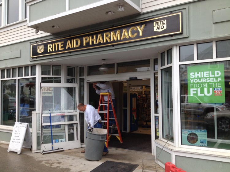 A worker replaces the front door of the Rite Aid pharmacy on Elm Street in Camden, following an overnight standoff that ended with the self-inflicted shooting death of a robbery suspect. 