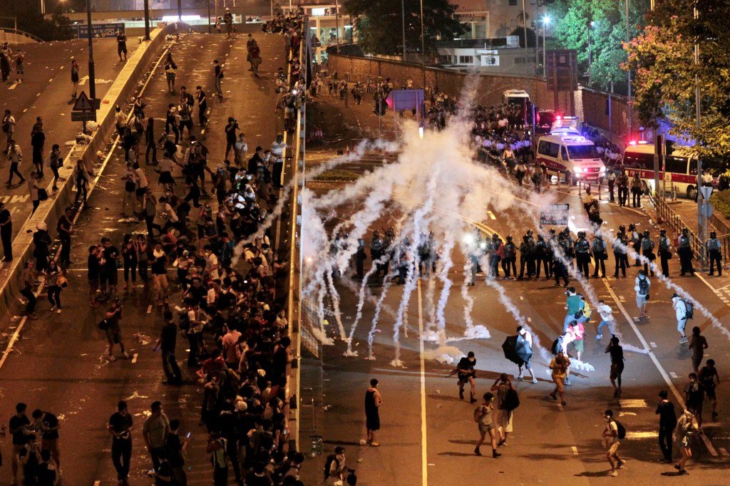 Riot police fire tear gas on student protesters occupying streets surrounding the government headquarters in Hong Kong early Monday. The Associated Press