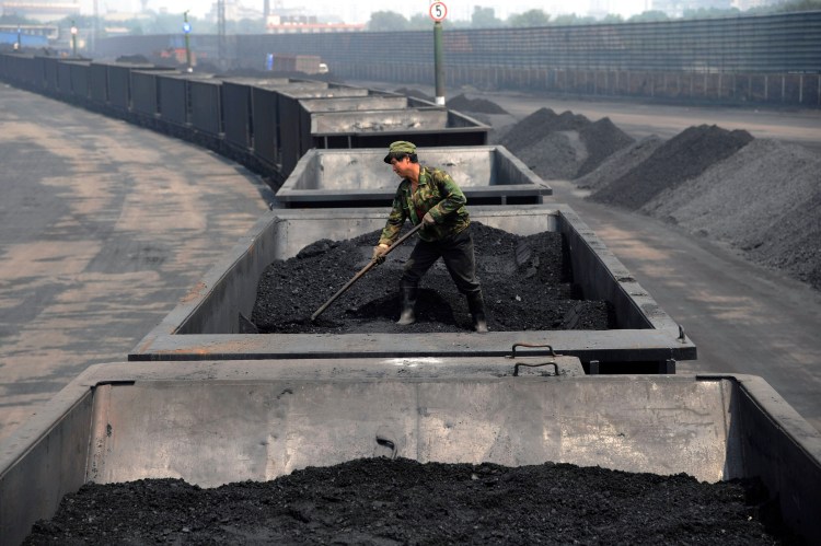 A worker levels the coal on a freight train in Taiyuan in northern China's Shanxi province. The Associated Press
