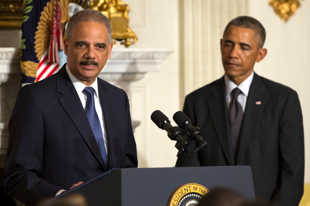 President Barack Obama, right, looks on as Attorney General Eric Holder speaks at the White House on Thursday in Washington. Holder is resigning after six years on the job. 