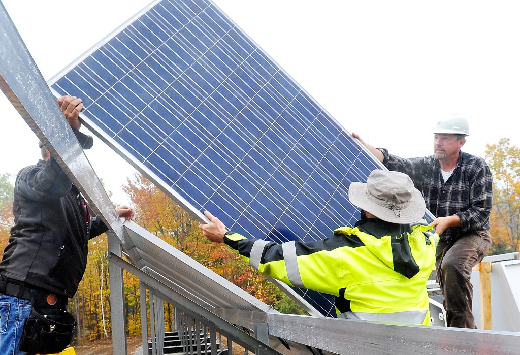 (FILE) Electricians install a solar electric panel into an 800-panel array at Mt. Abram Ski Area in October 2014.