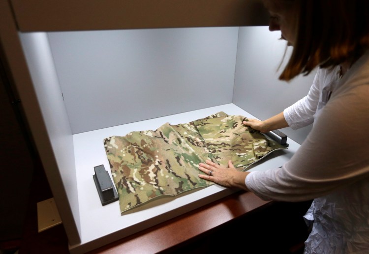 Clare King, of Providence, R.I., compares swatches of camouflage fabric in a shade box at Propel LLC, a textile technology research company, in Pawtucket, R.I. The shade box is used to  inspect camouflage designs and compare research fabrics to match a standard. King is president of Propel LLC. 