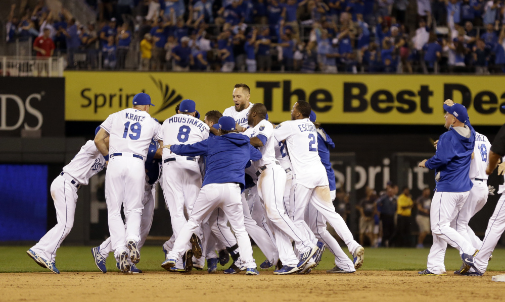 The Kansas City Royals mob teammate Salvador Perez after his walk-off single in the 12th inning to defeat the Oakland Athletics, 9-8. The Royals move on to play the Angels.