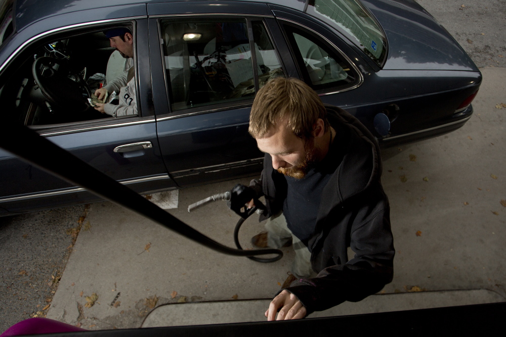 Paul Berg prepares to pump gas for a customer at Holly’s Super Gas. The average price of gas has fallen to $3.43 per gallon – down more than 30 cents since spring – and nationally may be as low as $3.10 by December.