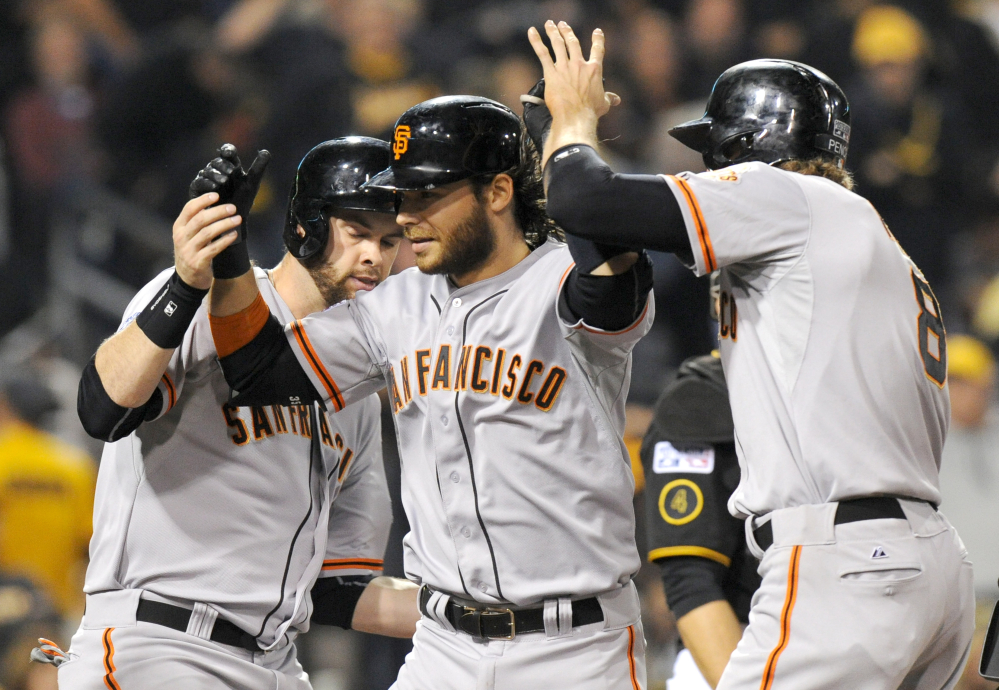 San Francisco Giants shortstop Brandon Crawford, center, is greeted by teammates Brandon Belt, left, and Hunter Pence, right, after hitting a grand slam against the Pittsburgh Pirates in the fourth inning of the NL wild-card playoff game Wednesday in Pittsburgh.