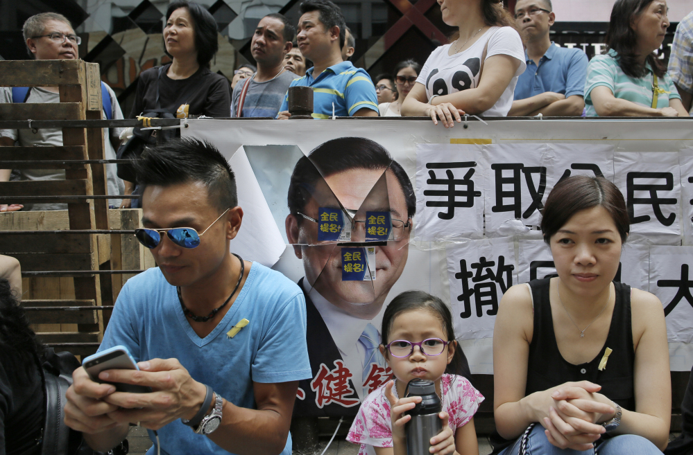 A pro-democracy protester, left, uses his smartphone while sitting in the street during a rally in Hong Kong on Thursday.