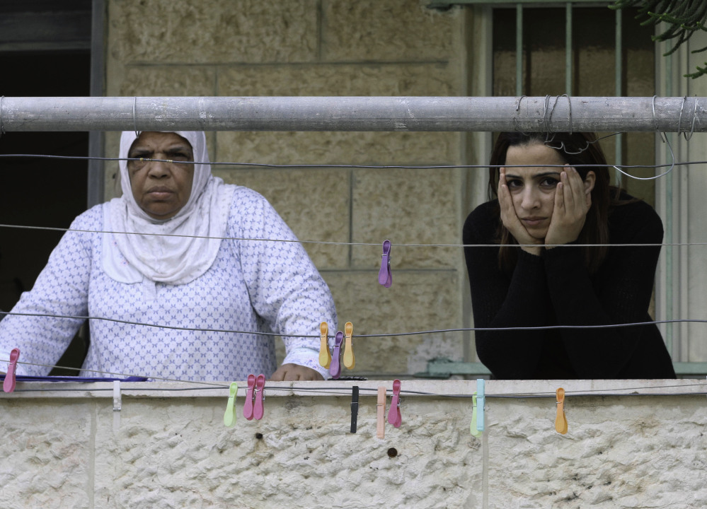 Palestinian women stand on their balcony overlooking a neighboring house that Jewish settlers moved into, in the Palestinian neighborhood of Silwan, east Jerusalem. About 500 Jews live in the area, and the newly purchased homes will allow for 200 more.