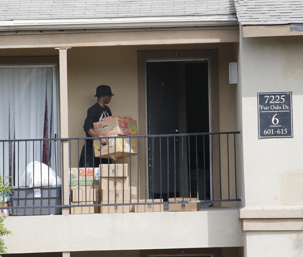 A young man retrieves food supplies left by the North Texas Food Bank and the Red Cross on the front stoop of an apartment at The Ivy Apartments complex, Thursday, Oct. 2, 2014, in Dallas, at The Ivy Apartments complex, Thursday, Oct. 2, 2014, in Dallas, where Thomas Eric Duncan, the Ebola patient who traveled from Liberia to Dallas last week, was staying.  Dallas County officials have ordered family members who had contact Duncan, quarantined in their home to prevent the spread of disease. (AP Photo/The Dallas Morning News, David Woo)  MANDATORY CREDIT; MAGS OUT; TV OUT; INTERNET USE BY AP MEMBERS ONLY; NO SALES
