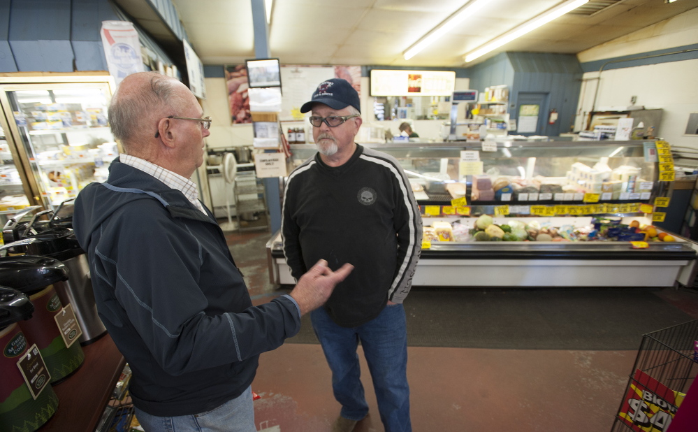 Retired Verso Paper mill worker Vernard Coffin, left, and current employee Stephen Bowden talk Thursday about the mill closure in front of the deli at Toziers Market on Main Street in Bucksport.