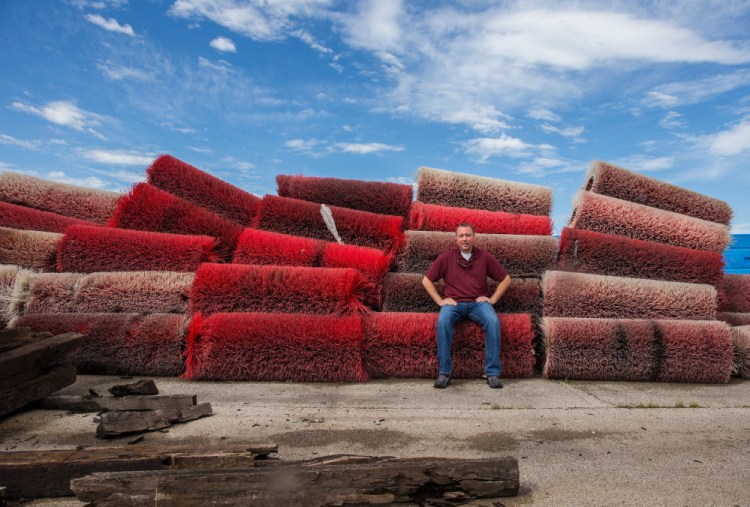Jerry Kessler, branch manager of Repurposed Materials, poses with street sweeper brushes at the warehouse in Manteno, Ill. Farmers buy the brushes for reuse as cattle back-scratchers.“They take the big brush and put it on a big pole (or) hang it from a tree or fence,” he said.