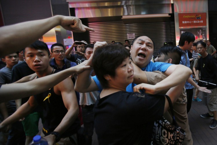 An instigator is taken from the crowd by pro-democracy student protesters after a scuffle with local residents in Mong Kok, Hong Kong, Saturday.