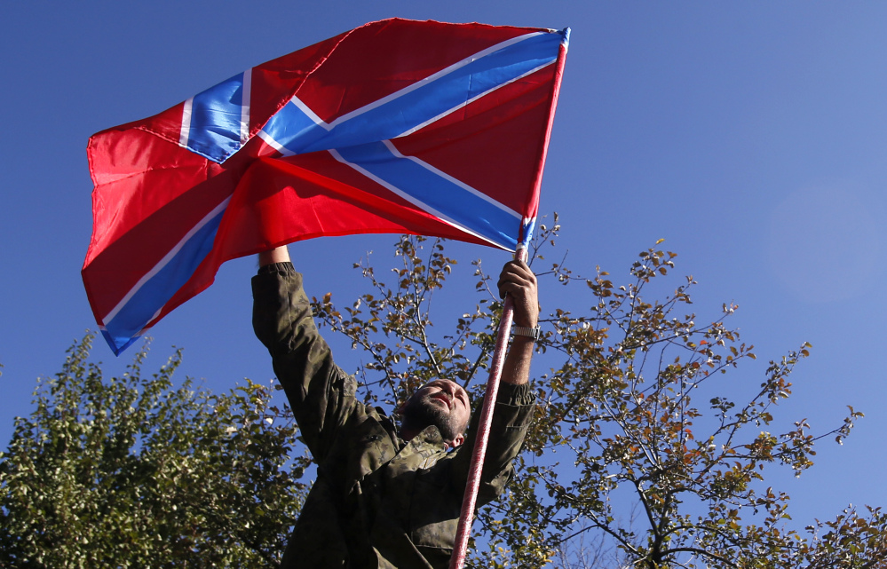 A pro-Russian rebel places a flag of the self-proclaimed Federal State of Novorossiya atop his truck before fighting began Friday near the airport in Donetsk, eastern Ukraine.
