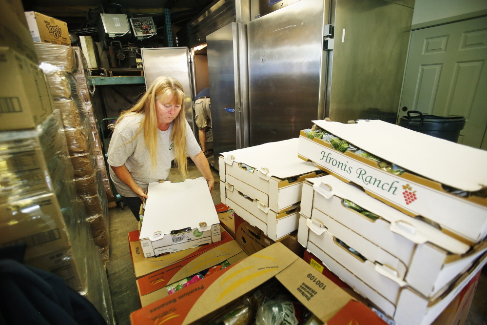 Jodi Bissonnette, director of York County Food Rescue in Alfred, unloads a carton of grapes from a pallet Monday at the group’s warehouse in Alfred.