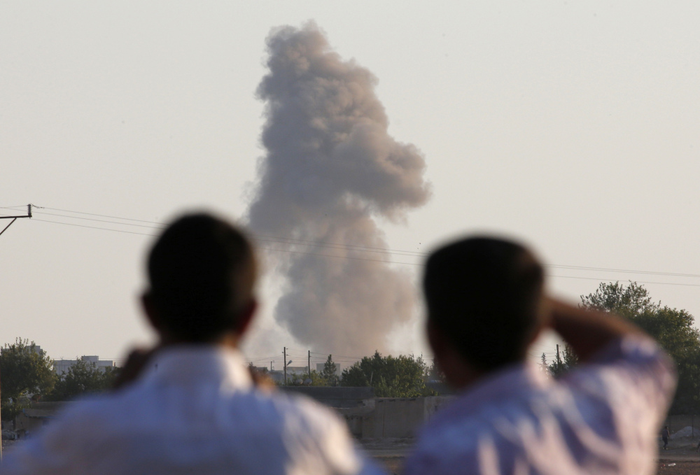 Turkish Kurds on the outskirts of Suruc, on the Turkey-Syria border, watch smoke rise after an airstrike in Kobani, Syria, where the fighting between the Islamic State group and Kurdish forces intensified Tuesday.