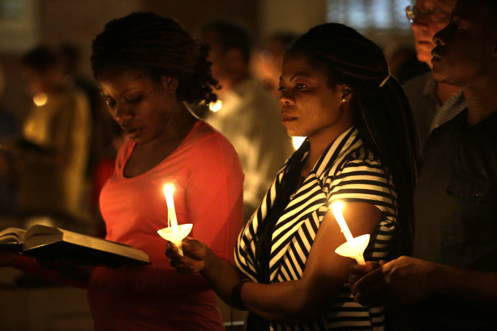 Princess Duo, left, and Mamie Mangoe, right, natives of Liberia who live in Dallas, hold candles as they pray during a service at Wilshire Baptist Church dedicated to Thomas Eric Duncan, who died Wednesday from the Ebola virus.