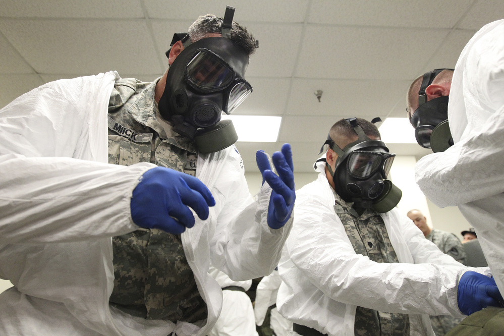 Sgt. Joel Miick, left, and Spc. Michael Potts don gas masks while training with the rest of the 36th Engineer Brigade at Fort Hood, Texas, on how to put on protective clothing and gloves Thursday. The brigade is set to deploy to Liberia where they will build temporary medical facilities to hel fight the Ebola virus outbreak.