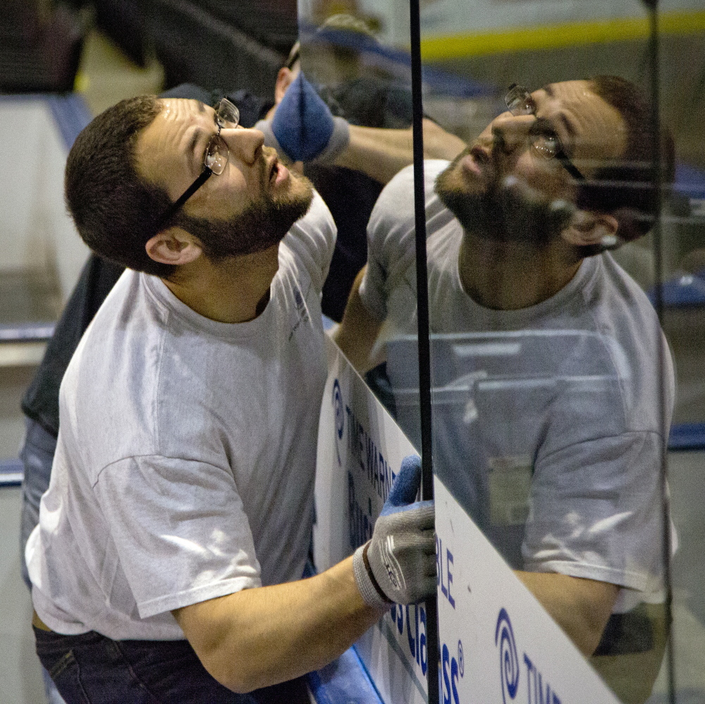 Zac Leo fits glass to the boards Friday in preparation for the Portland Pirates home opener.